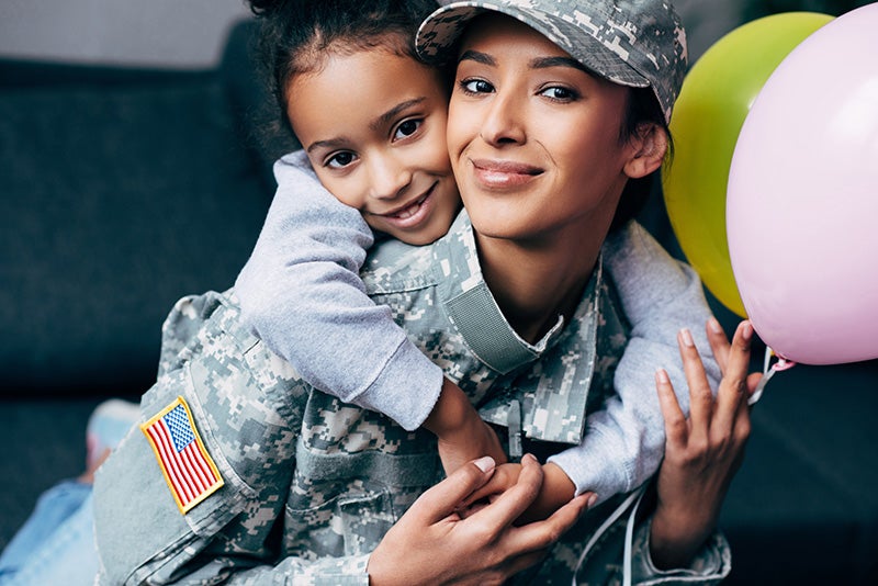 Military woman hold a kid on his shoulders